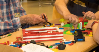viele Hände bauen Legohaus